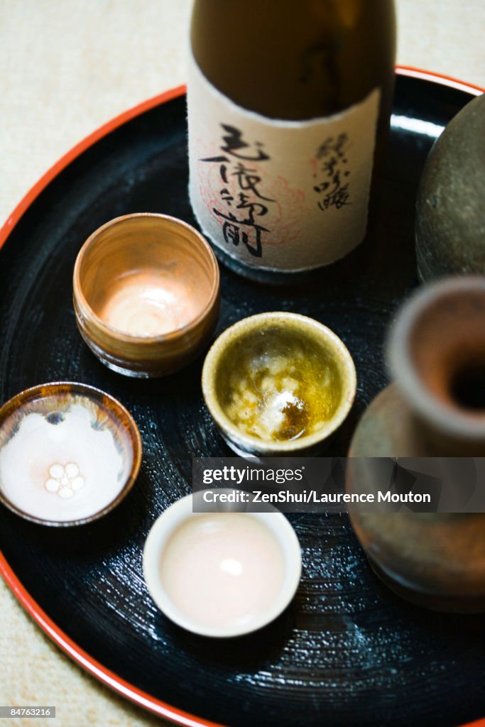 Bottle of sake and sake cups on tray, close-up