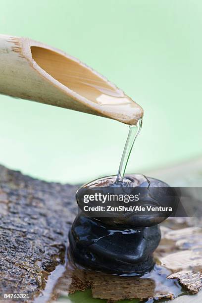 wooden spout pouring water over stack of stones - natale stockfoto's en -beelden
