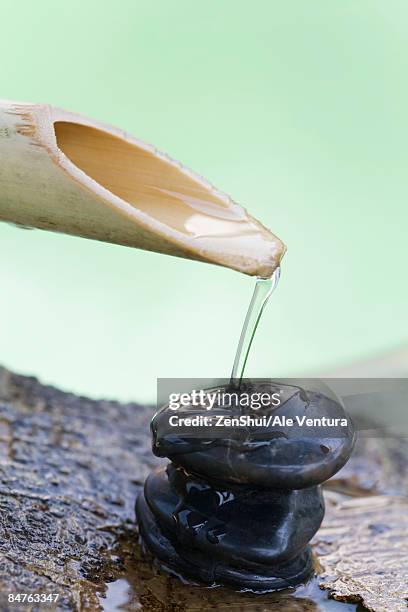 bamboo spout pouring water on stack of stones - natale stockfoto's en -beelden