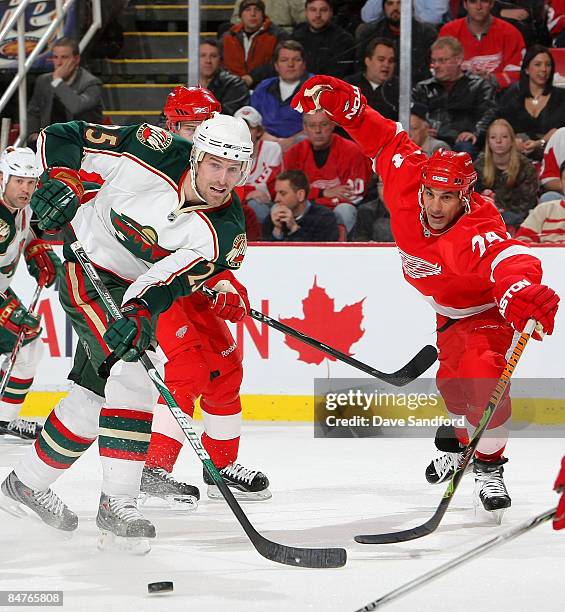 Eric Belanger of the Minnesota Wild dishes a pass off as Chris Chelios of the Detroit Red Wings defends during their NHL game at Joe Louis Arena...