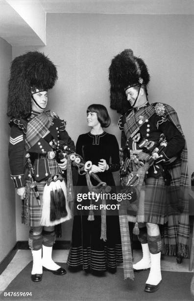 Mireille Mathieu en compagnie de deux Ecossais en tenue traditionnelle pour un spectacle en juin 1972 a Londres, Royaume-Uni.