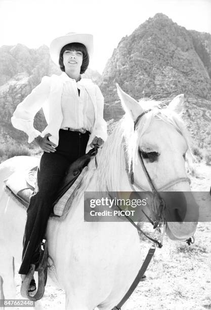 Mireille Mathieu fait une randonnee a cheval coiffee d'un chapeau de cow-boy durant sa tournee americaine en juin 1978 aux Etats-Unis.