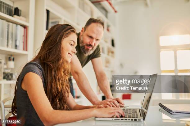 solo padre ayudar a la adolescente con su tarea. - monoparental fotografías e imágenes de stock