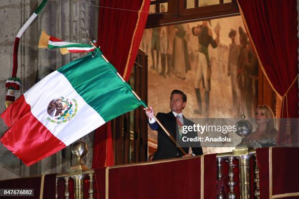 Mexican President Enrique Pena Nieto waves the Mexican National Flag during the traditional "El Grito" or "The Shout" at the balcony of the National...