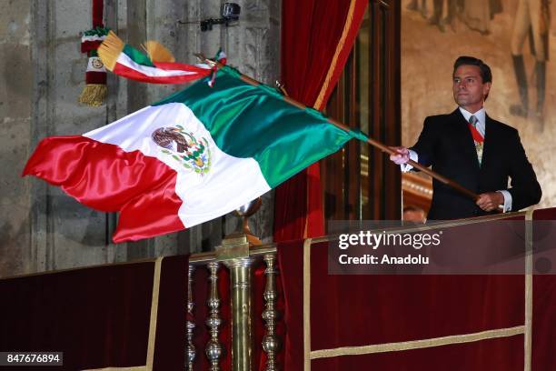 Mexican President Enrique Pena Nieto waves the Mexican National Flag during the traditional "El Grito" or "The Shout" at the balcony of the National...