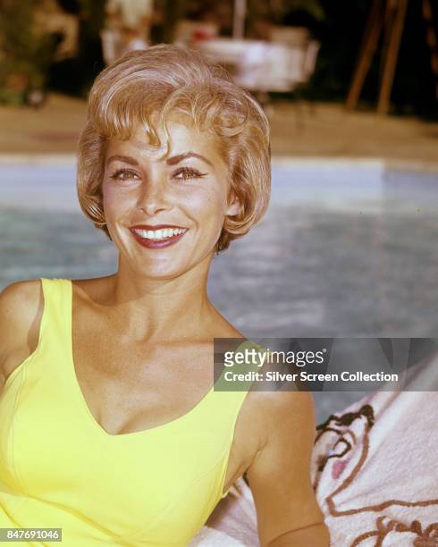 American actress Janet Leigh smiles smiles from a lounger near a swimming pool, circa 1955.