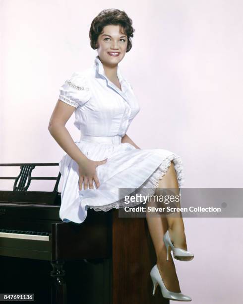 American pop singe Connie Francis sits on a piano, circa 1965.