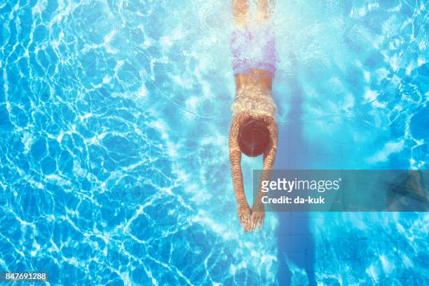 fröhlicher junge tauchen im schwimmbad - floating on water stock-fotos und bilder