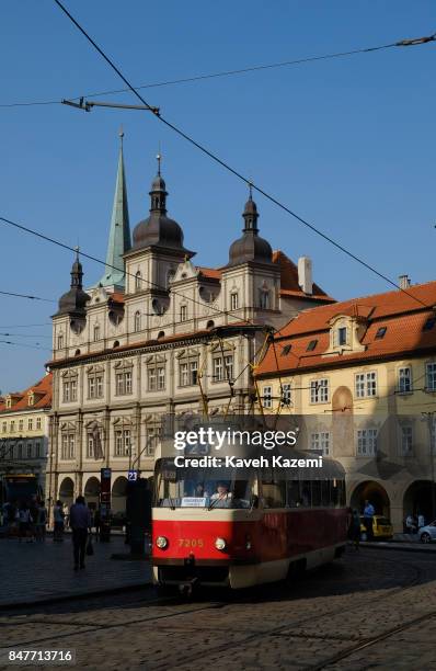 An old fashioned red tram goes past historical monuments in old town on July 18, 2017 in Prague, Czech Republic. Prague is the capital and largest...