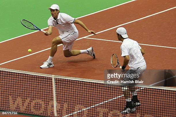Tomas Berdych of Czech Republic volleys with partner Jurgen Melzer of Austria looking on during their doubles quarterfinal match against Jeff Coetzee...