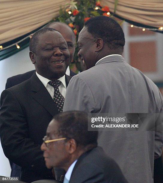 Zimbabwe's Prime Minister Morgan Tsvangirai congratulates new Minister of Defeance Emmerson Mnangagwa as Zimbabwe President Robert Mugabe looks on at...