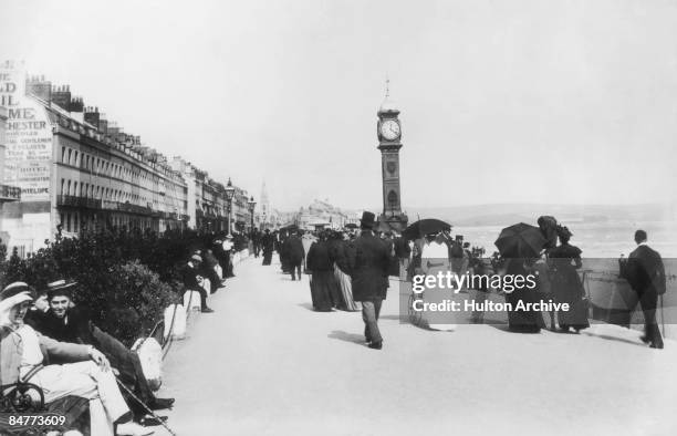 Holidaymakers walking past Queen Victoria's Jubilee Clock on the esplanade at Weymouth, Dorset, circa 1890.