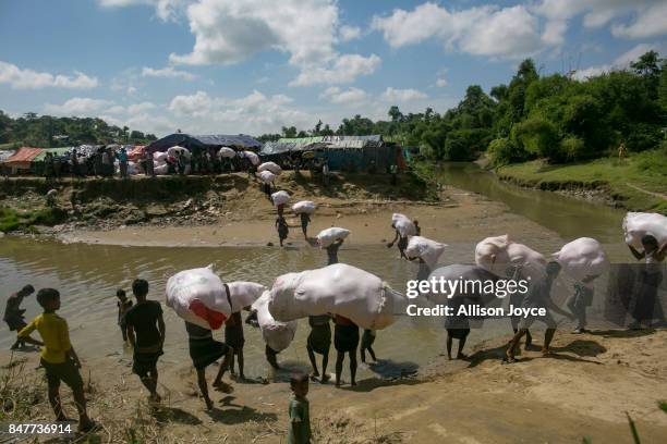Rohingya carry donations into no man's land where Rohingya have set up refugee camps, September 16, 2017 in Tombru, Bangladesh. Nearly 400,000...
