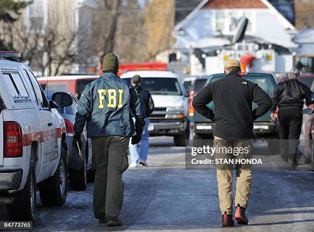 Investigators, including one from the FBI walk to the scene of a Continental Airlines crash February 13, 2009 in Clarence Center, New York, just...