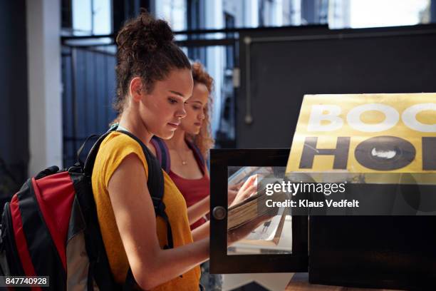 young women with backpacks smiling, while choosing books - summer university day 2 foto e immagini stock