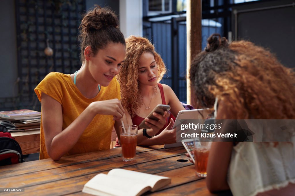 Young women looking at their own different phones and tablet