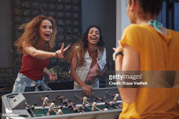 three young women playing foosball at youth hostel - dama game fotografías e imágenes de stock