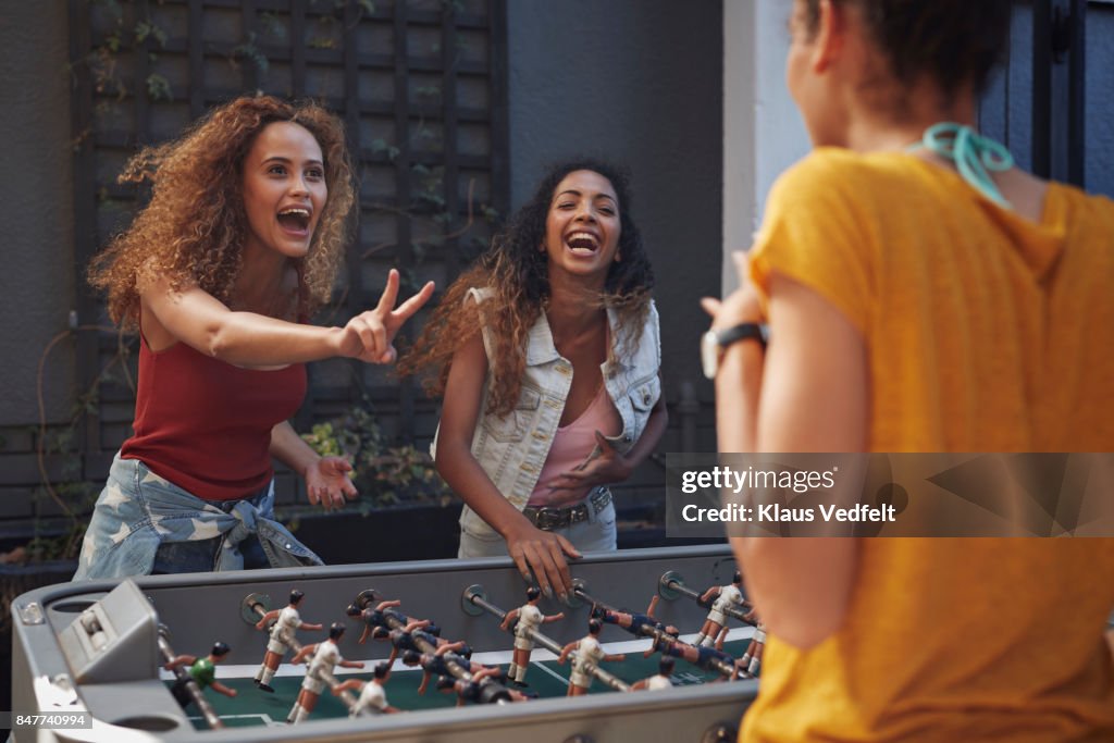 Three young women playing foosball at youth hostel
