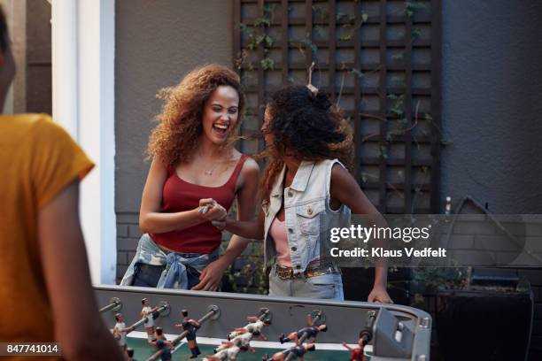 three young women playing foosball at youth hostel - fun student stockfoto's en -beelden