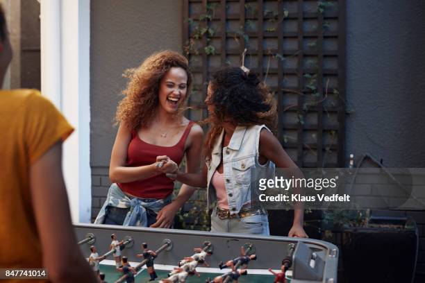 three young women playing foosball at youth hostel - campus tour stock pictures, royalty-free photos & images