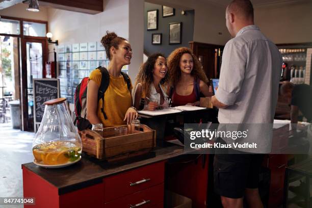 young women signing in to youth hostel - booking hotel foto e immagini stock
