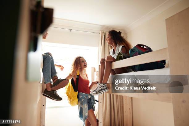 young women arriving to room with bunk beds, at youth hostel - viaje barato fotografías e imágenes de stock