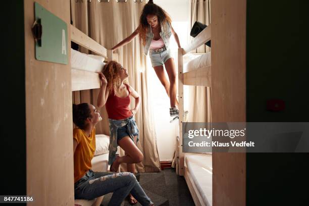 young women arriving to room with bunk beds, at youth hostel - hostel room stock-fotos und bilder