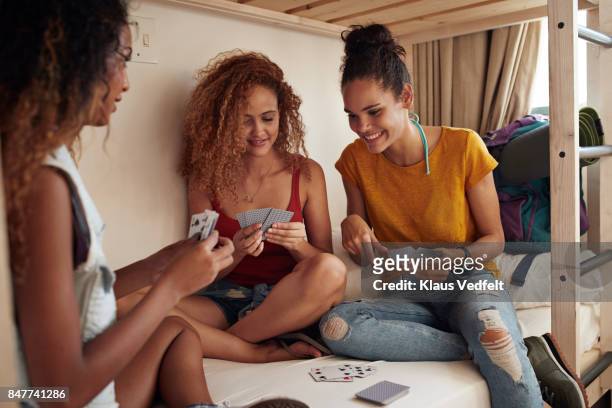 young women playing cards in bunk bed, at youth hostel - kaartspel stockfoto's en -beelden