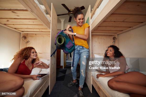 young woman arriving at hostel room, two other women laying in bunk beds - girls trip film stockfoto's en -beelden