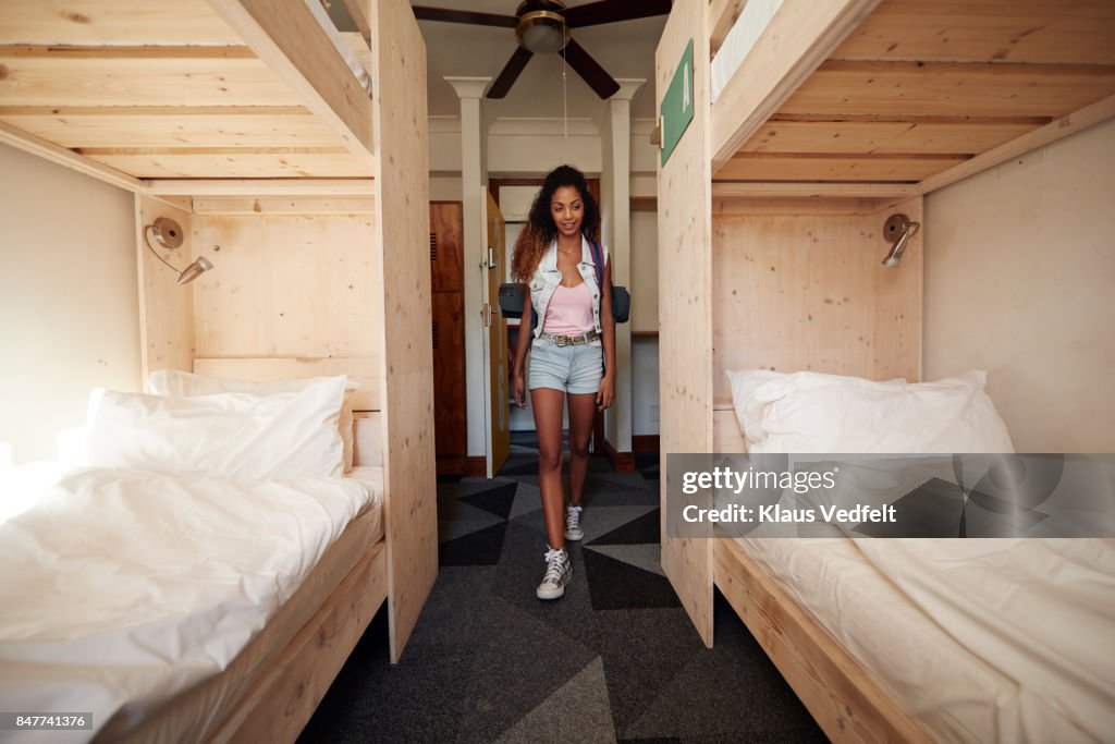 Young Woman With Backpack Arriving At Empty Hostel Room High-Res