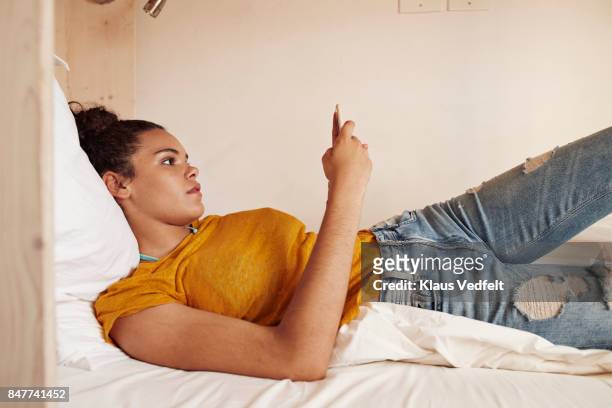 young woman checking phone in bunk bed - beautiful college girls stock pictures, royalty-free photos & images