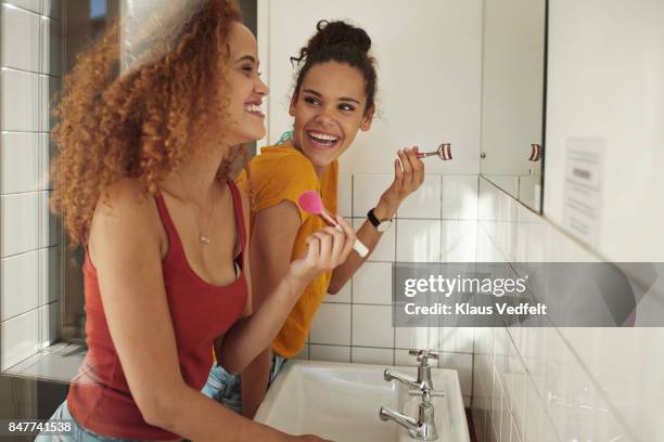 friends getting ready in front of mirror in bathroom - make up photos et images de collection