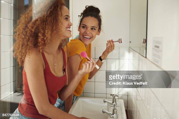 friends getting ready in front of mirror in bathroom - friends women makeup stockfoto's en -beelden
