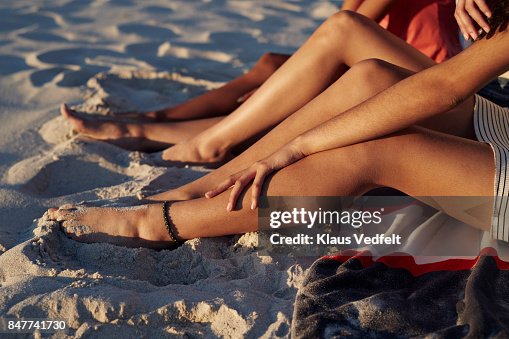 Close-up of three young womens legs, on sandy beach Close-up of three young womens legs, on sandy beach