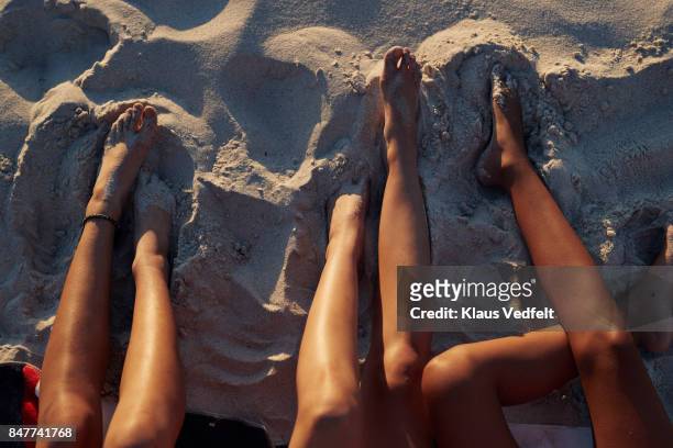 close-up of three young womens legs, on sandy beach - young teen girl beach ストックフォトと画像
