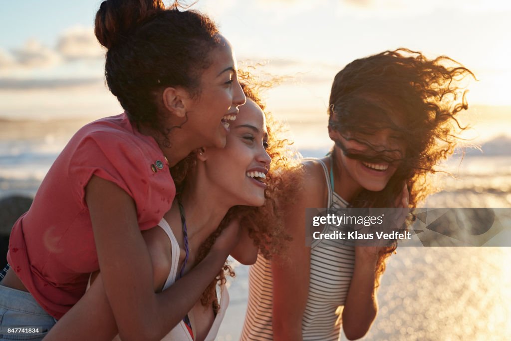 Young women piggybacking on sandy beach