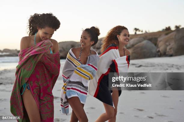 three friends walking together on the beach, after swim - envuelto en una toalla fotografías e imágenes de stock