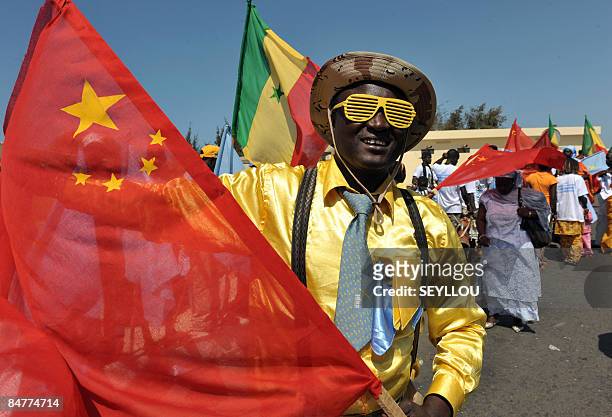 Senegalese man waves a Chinese flag on February 13, 2009 in Dakar as he waits for Chinese President Hu Jintao's arrival from Dakar aiport.China's...