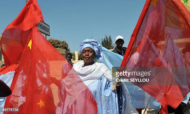 Senegalese woman waves Chinese flags on February 13, 2009 in Dakar as she waits for Chinese President Hu Jintao's arrival from Dakar aiport.China's...