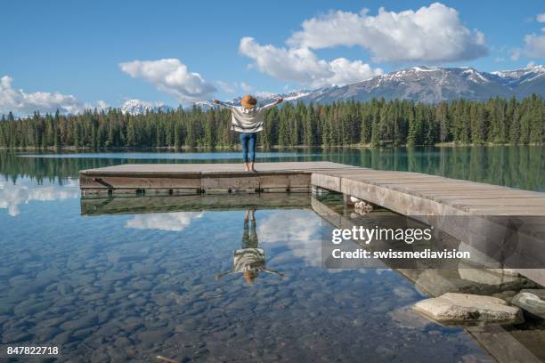 young woman arms outstretched on lake pier - jasper stock pictures, royalty-free photos & images