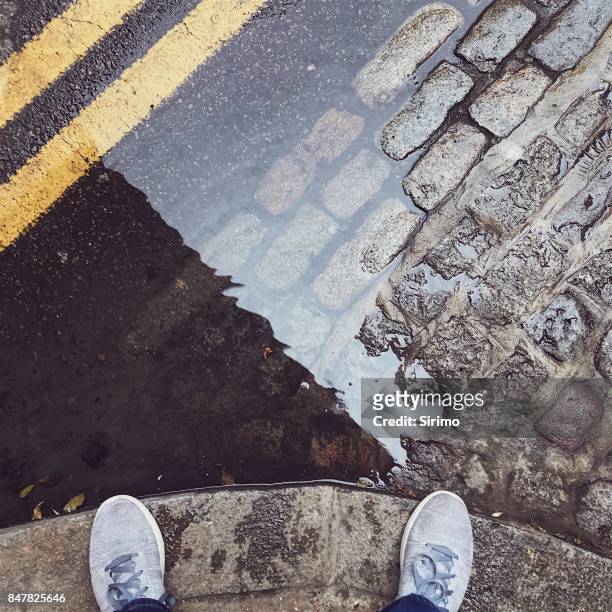 feet next to a london puddle - cobblestone puddle stock pictures, royalty-free photos & images