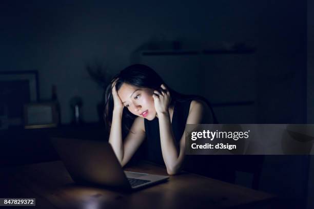 stressed and frustrated businesswoman working on laptop till late at work - überarbeitung stress stock-fotos und bilder