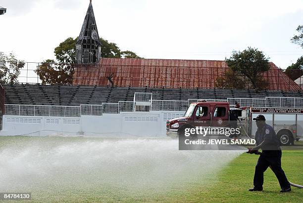 Firefighter waters the outfield of the Antigua Recreation Ground to prepare it for the third Test match between England and West Indies after the...