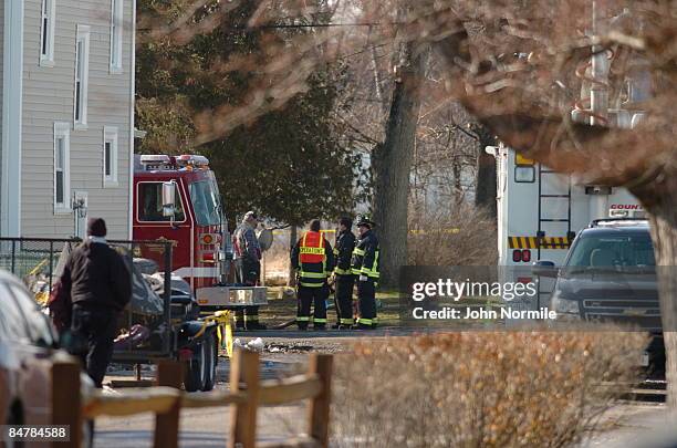 Firefighters gather near the crash site of Continental flight 3407 February 13, 2009 in Clarence, outside of Buffalo, New York. The plane crashed...