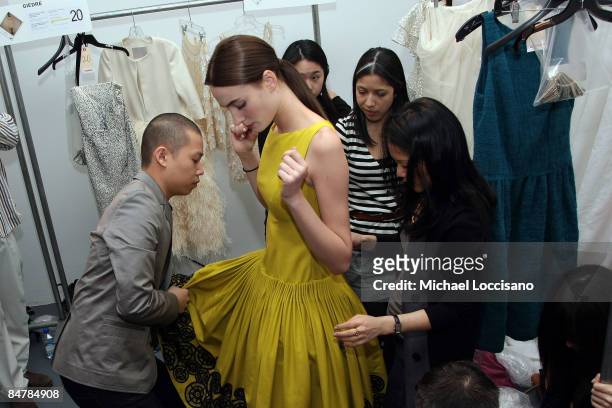 Designer Jason Wu helps a model with her dress backstage at the Jason Wu Fall 2009 fashion show during Mercedes-Benz Fashion Week at Exit Art on...