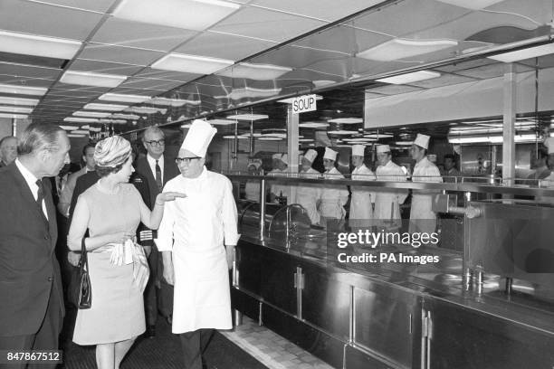 Queen Elizabeth II questions one of the experts as she tours the kitchens during her visit to the QE2 at Southampton, on the eve of the liner's...