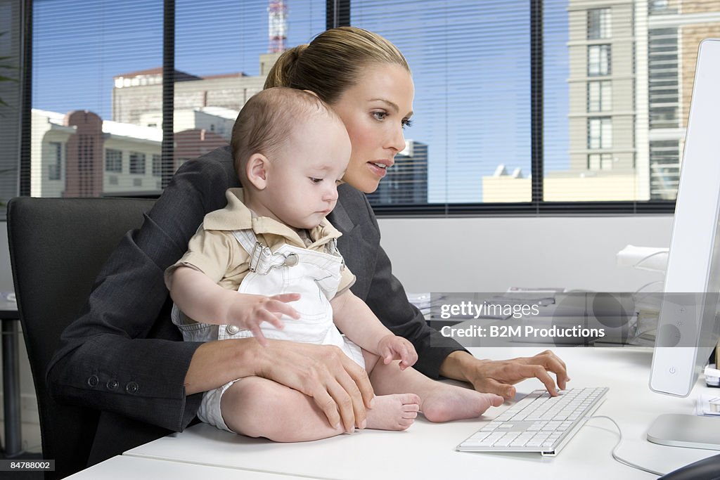 Baby sitting on desk of a businesswoman