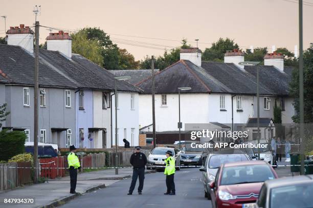 An investigator enters a house as police stand guard during a police raid in Sunbury, Surrey near London on September 16, 2017. British police raided...