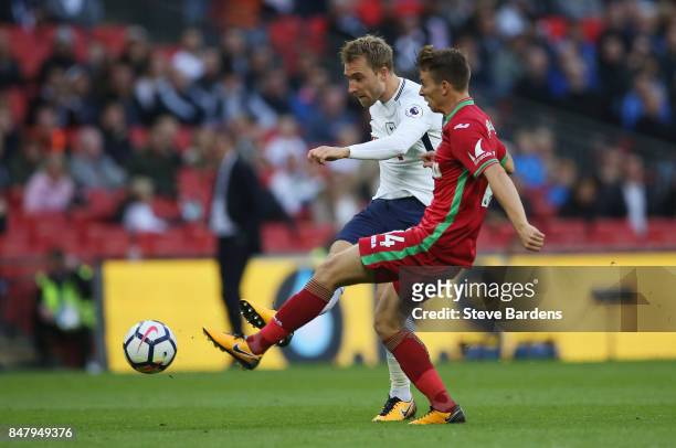 Christian Eriksen of Tottenham Hotspur shoots while under pressure from Tom Carroll of Swansea City during the Premier League match between Tottenham...