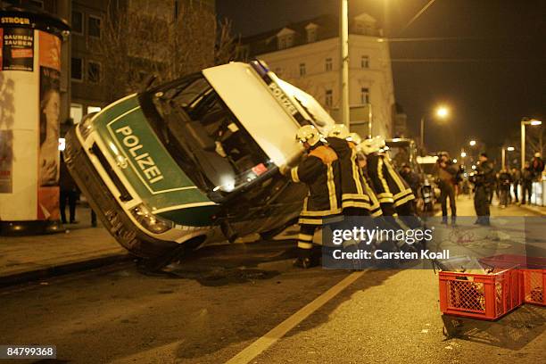 Firefighter puts up a knocked over police car after a demonstration on February 14, 2009 in Dresden, Germany. Reportedly over 10,000 people attended...